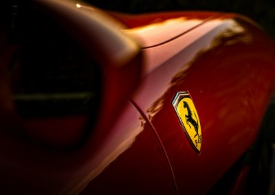 Primer plano de la parte trasera lateral de un Ferrari rojo, mostrando su logotipo característico